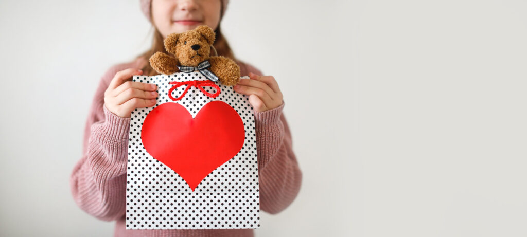 Mädchen mit einem weichen Teddybär in einer Geschenkidee als Wundertüte