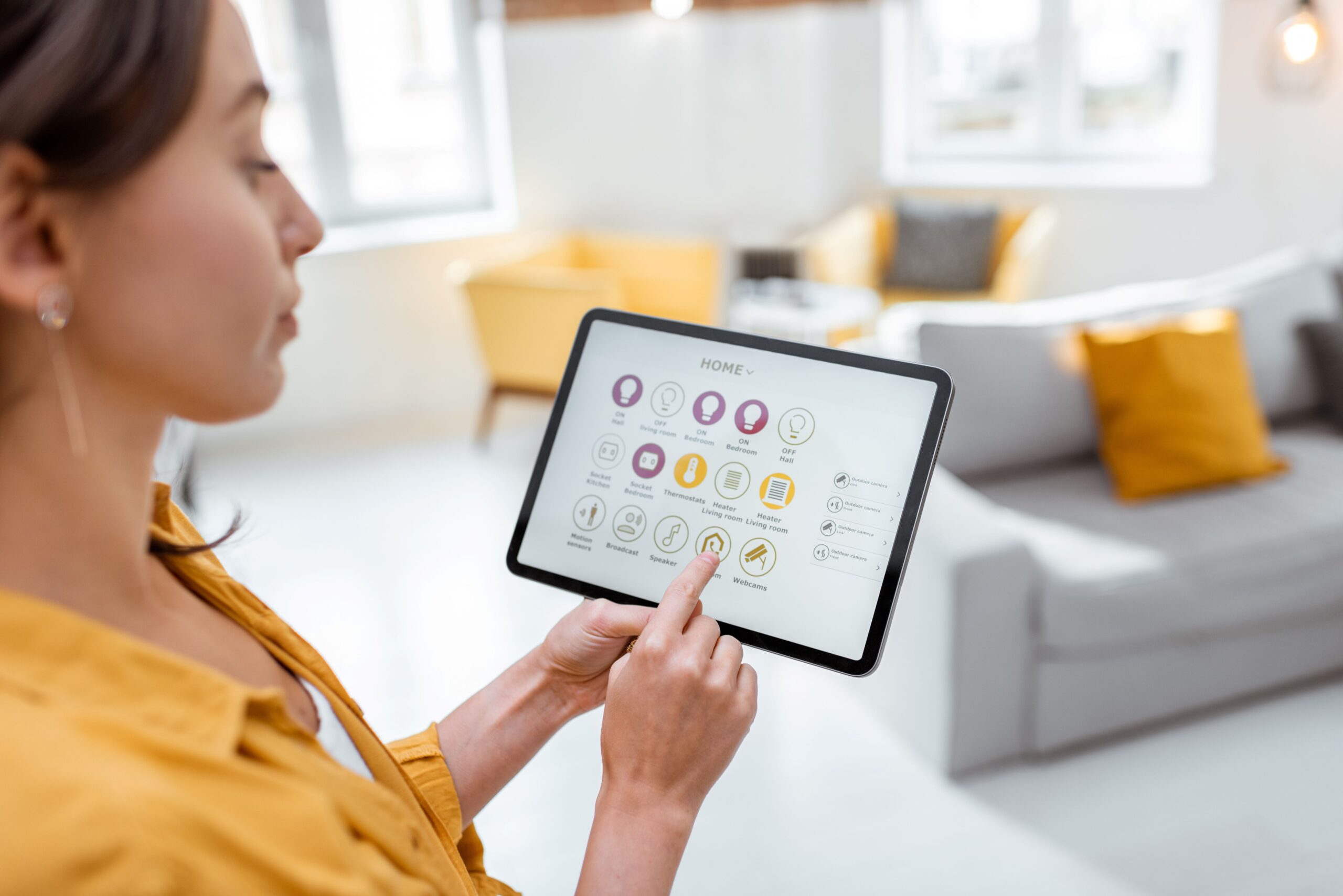 Eine Person ist an einem Tablet und stellt etwas an einem smart home systeme ein 