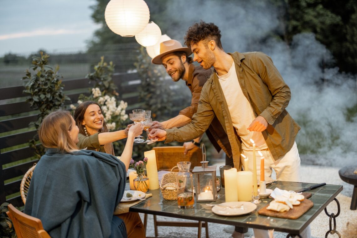 Freunde geniessen froehliche Stimmung bei Gartenparty am Abend | Terrassenüberdachung